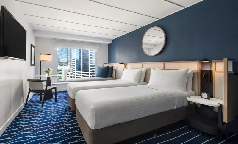 Une chambre d'hôtel moderne avec deux lits simples et une vue sur la ville.