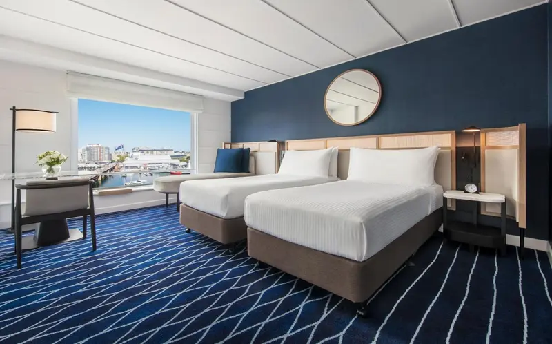Chambre avec deux lits simples et vue sur un port.