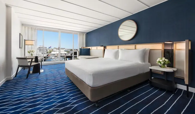 Chambre lumineuse avec un grand lit et vue sur le port.