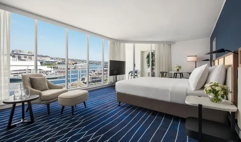 Chambre lumineuse avec un grand lit et une vue sur le port.