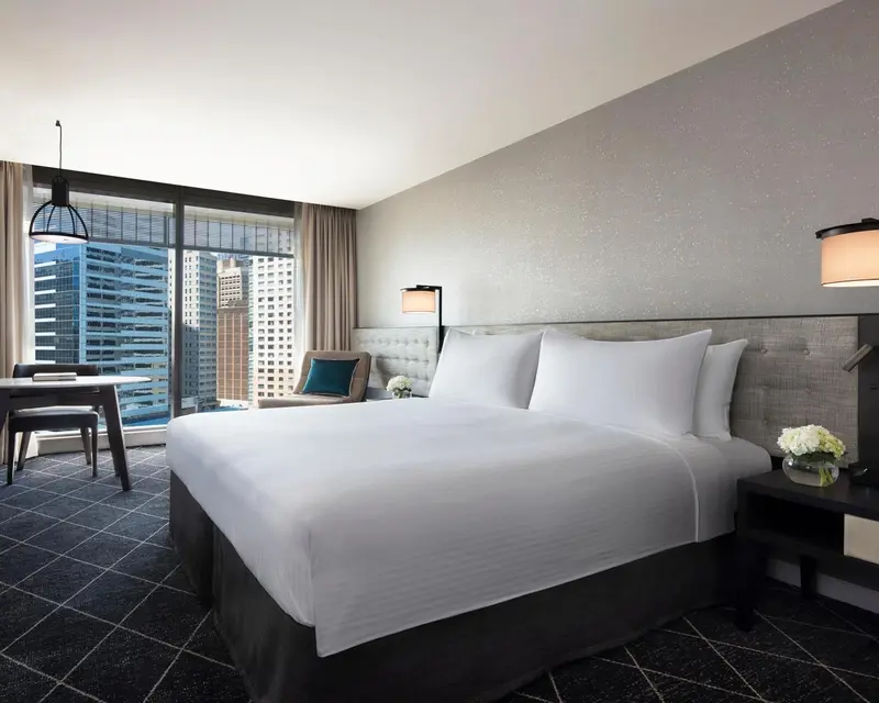 Chambre moderne avec un grand lit et une vue sur la ville.