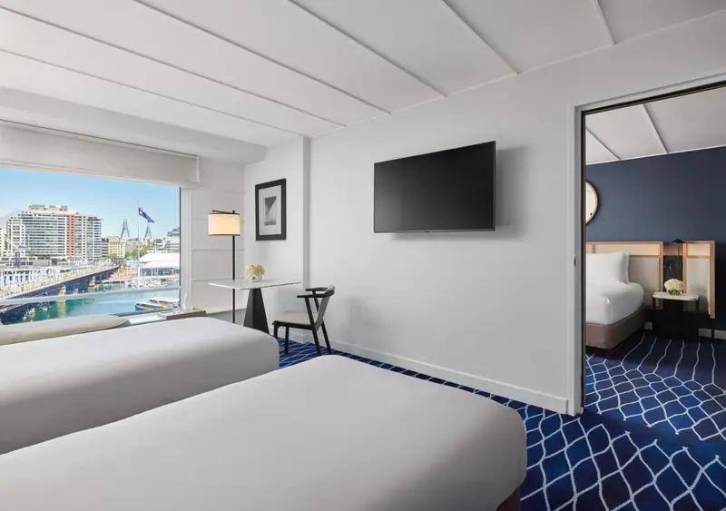 Une chambre lumineuse avec deux lits et une vue sur le port.