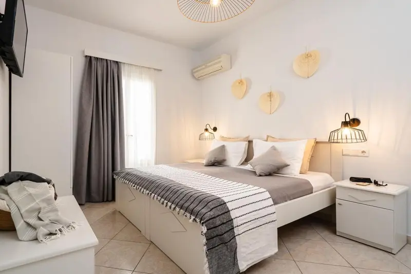 Une chambre lumineuse avec un grand lit recouvert d'une couverture grise et de coussins.