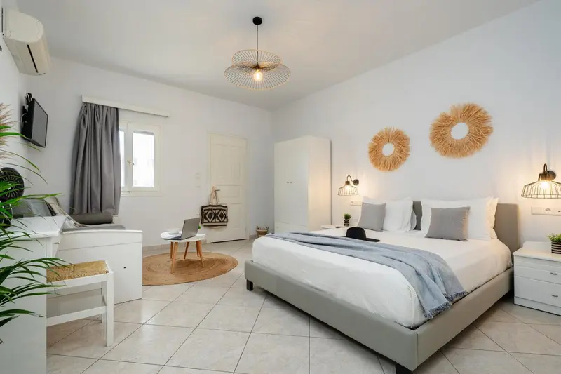 Chambre lumineuse avec un grand lit et une décoration murale en fibres naturelles.