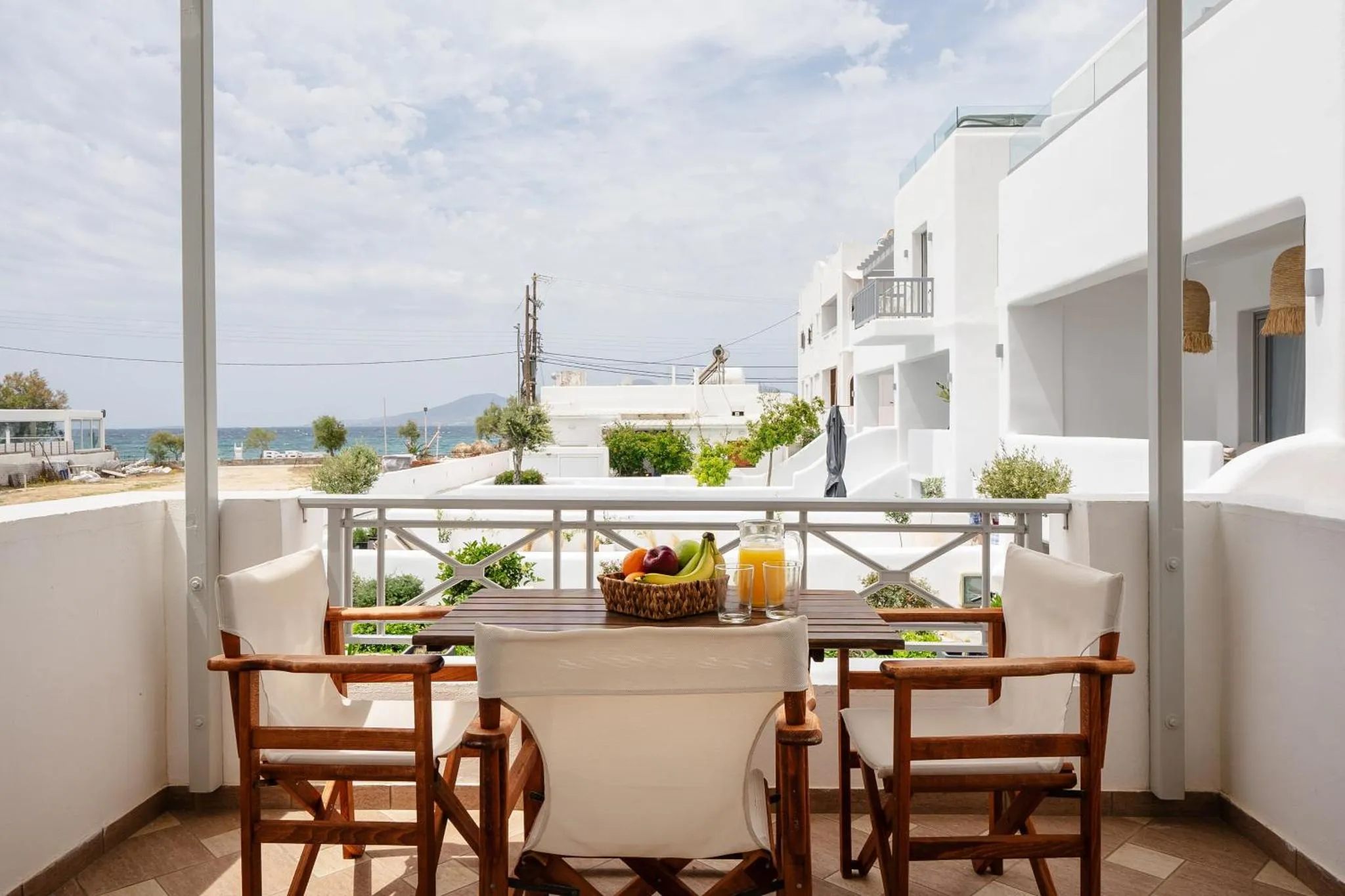 Une table et des chaises sont disposées sur une terrasse avec vue sur la mer et les bâtiments environnants.
