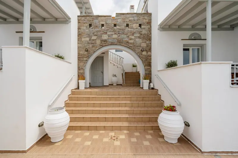 Entree d'un batiment blanc avec un escalier menant a une porte bleue.
