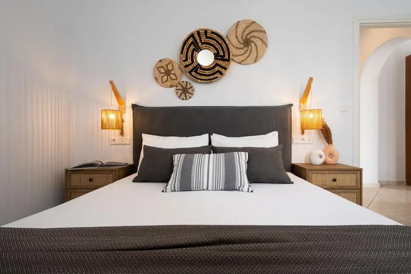 Une chambre avec un grand lit recouvert de textiles blancs et gris.
