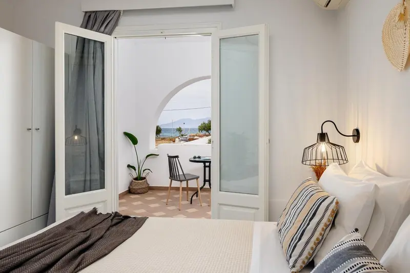 Une chambre lumineuse s'ouvre sur un balcon avec vue sur la mer.