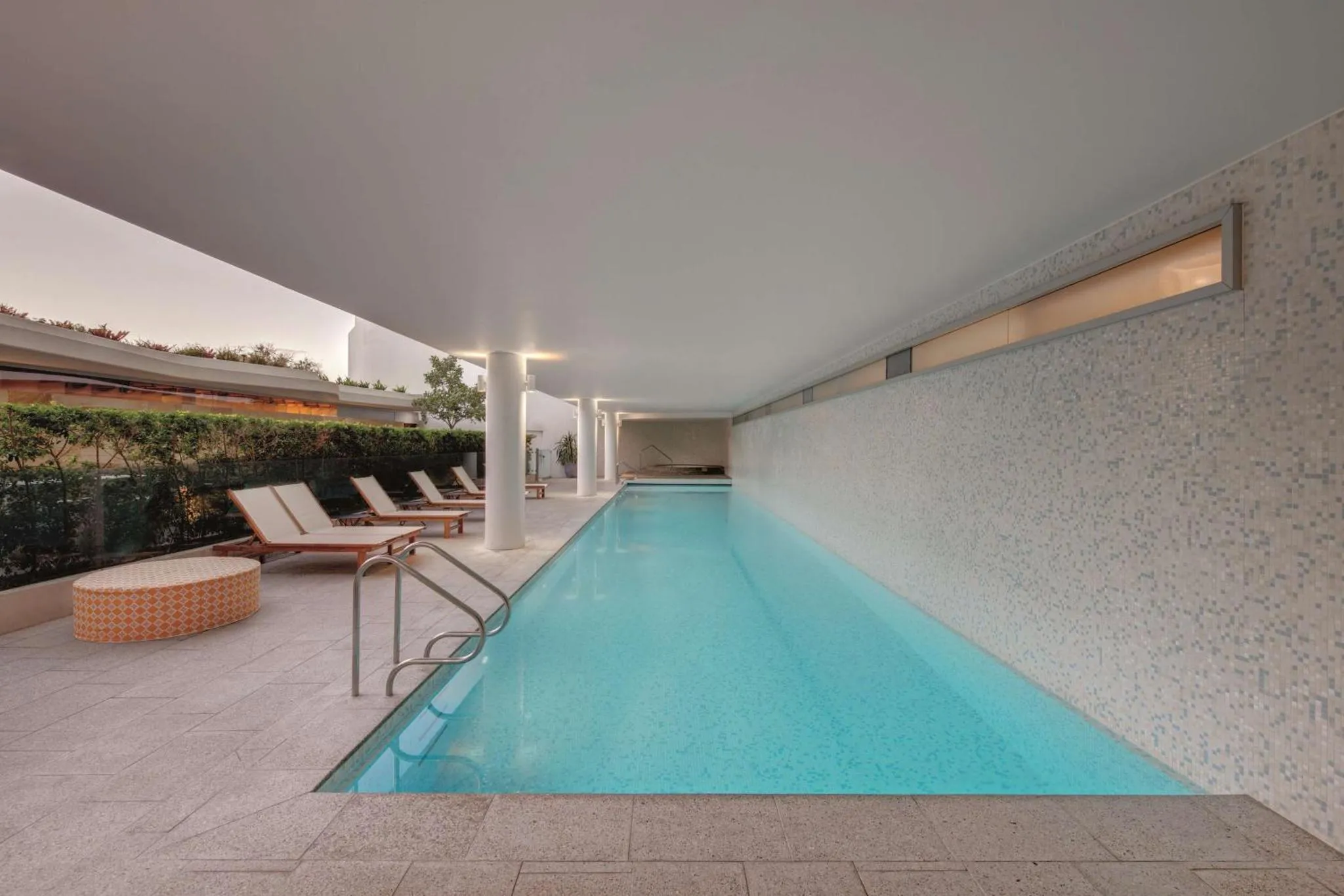 Une piscine rectangulaire avec des transats sur le bord.