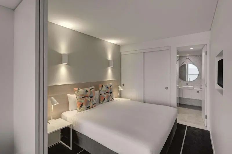 Une chambre lumineuse avec un grand lit et des oreillers colorés.