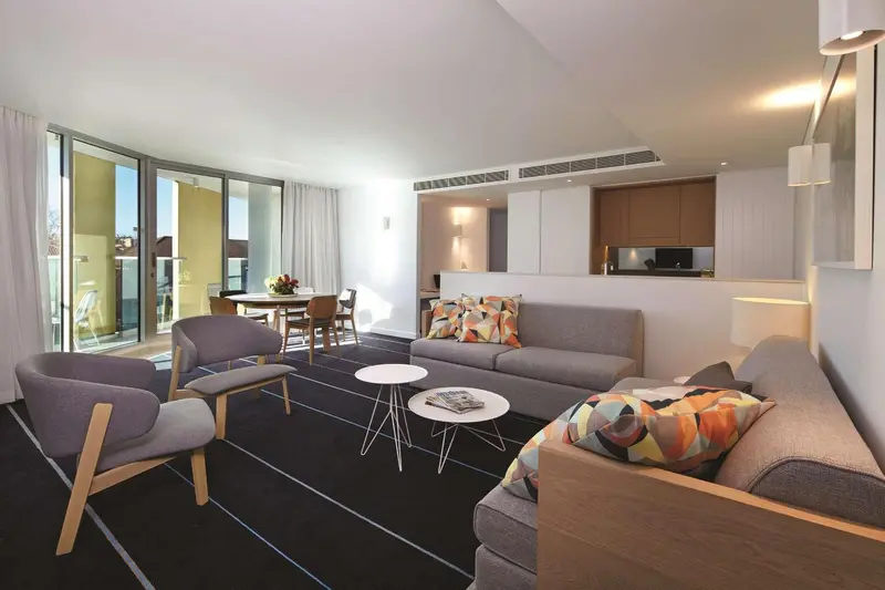 Un salon moderne avec canapés et fauteuils face à une table basse et un espace repas.