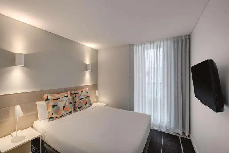 Une chambre d'hôtel moderne avec un lit double et une télévision murale.