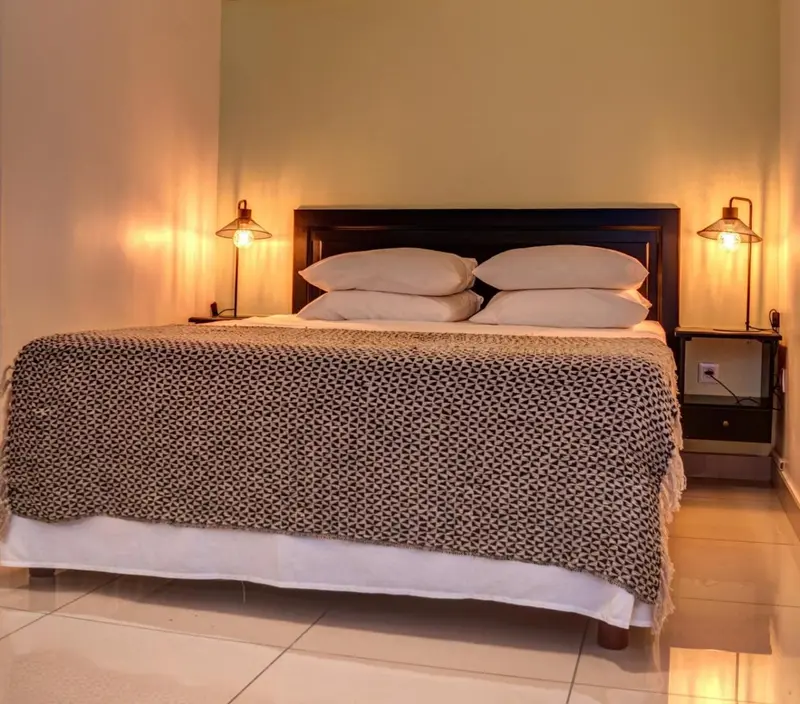 Une chambre lumineuse avec un grand lit recouvert d'une couverture à motifs.