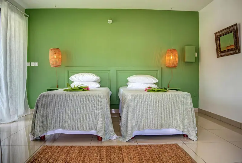 Une chambre lumineuse avec deux lits simples décorés de fleurs.