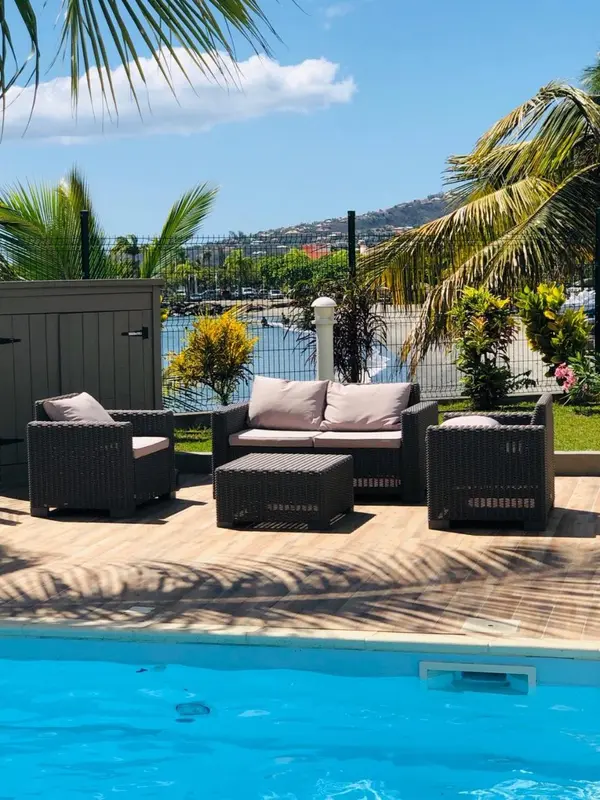 Mobilier de jardin disposé au bord d'une piscine avec une vue sur la mer.