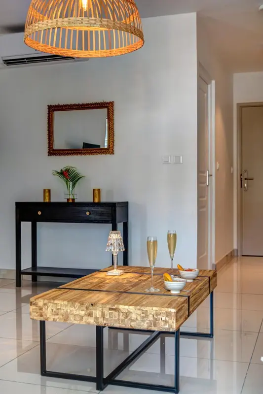 Une table basse en bois et deux verres de champagne sont posés dans une pièce lumineuse.