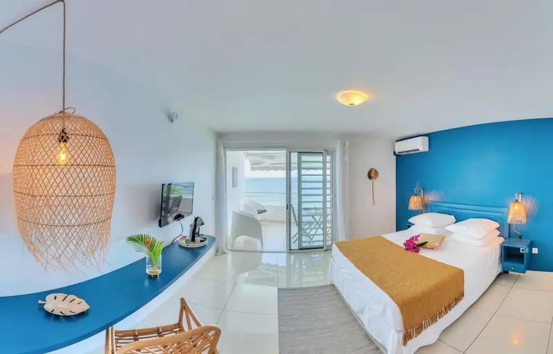 Chambre lumineuse avec un lit double et vue sur la mer.