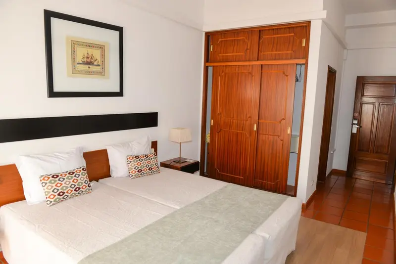 Une chambre lumineuse avec un grand lit et un placard en bois.