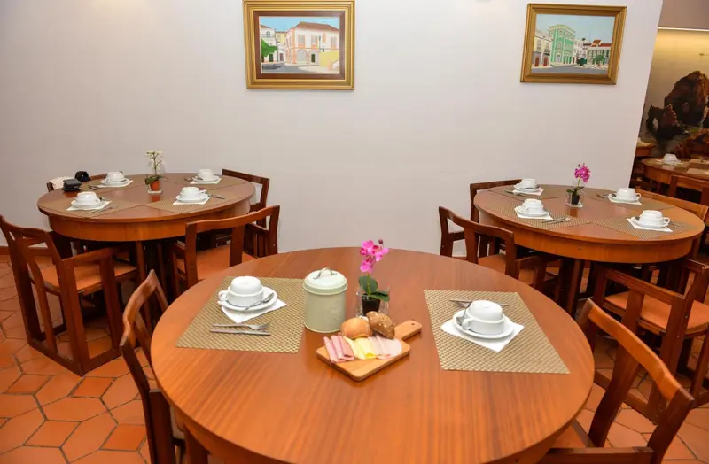 Tables rondes dressées pour le petit-déjeuner dans une salle lumineuse.