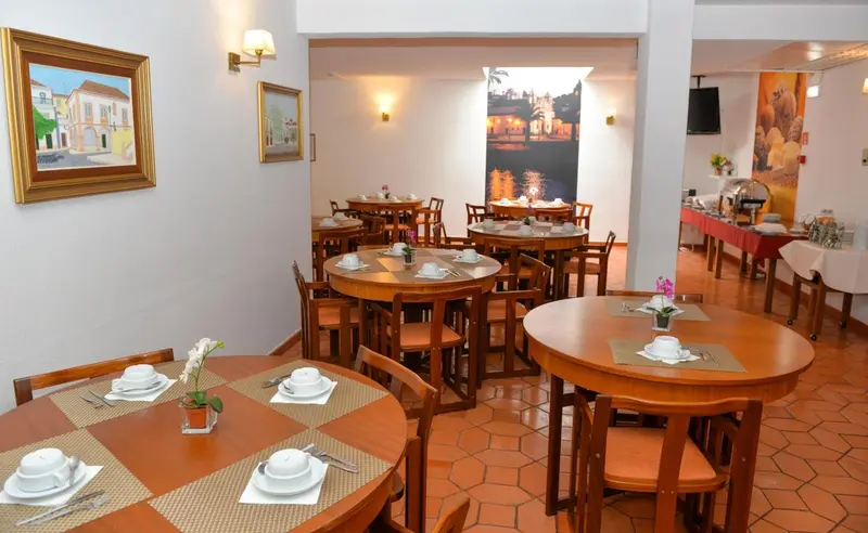 Une salle lumineuse avec des tables rondes dressées pour le repas.