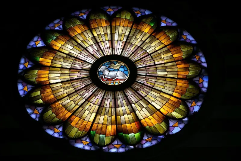 Rosace vitrail colorée avec motif central d'un agneau.