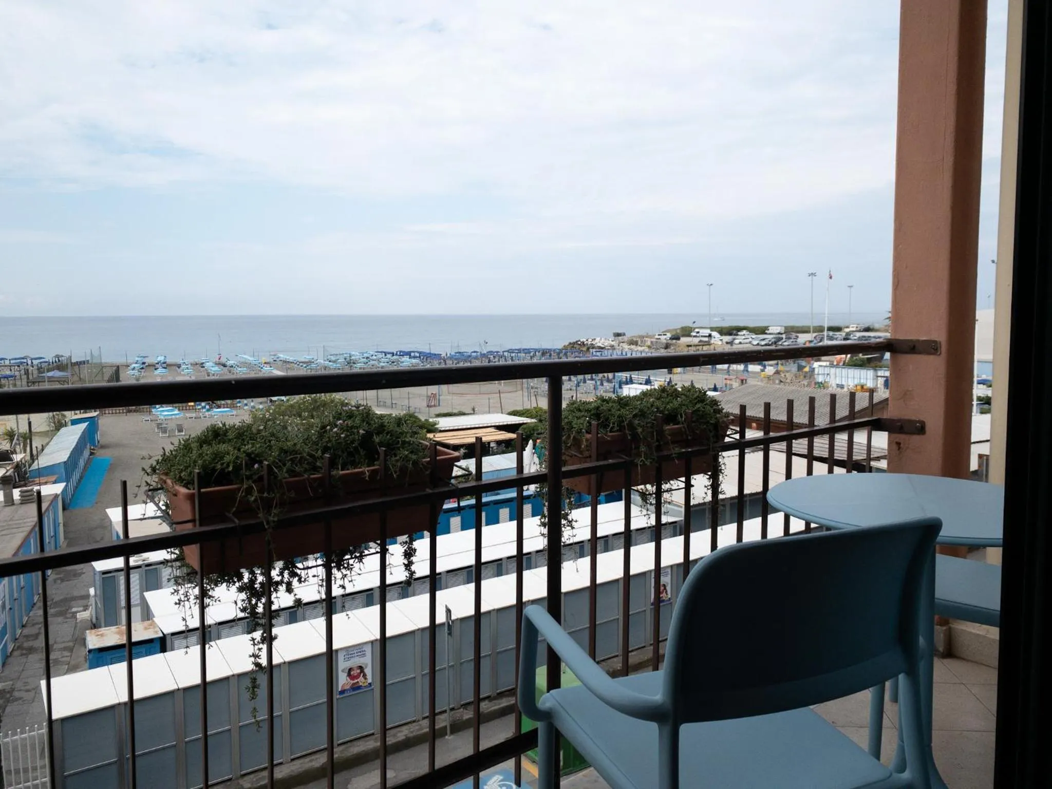 Vue d'une terrasse avec une table et des chaises donnant sur la mer et une plage.