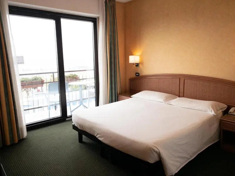Une chambre lumineuse avec un grand lit donnant sur une terrasse.