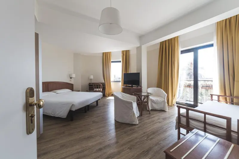 Une chambre lumineuse avec un lit double et un coin salon.