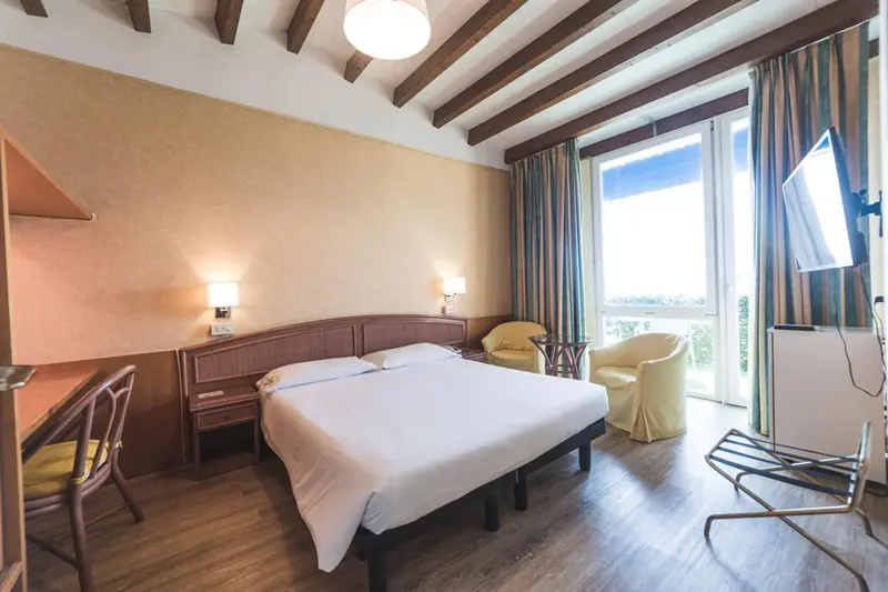 Une chambre lumineuse avec un lit double et un coin salon.