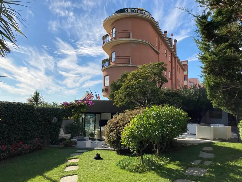 Bâtiment rose à plusieurs étages avec des balcons et une végétation luxuriante.