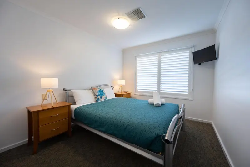 Une chambre lumineuse avec un lit double et des tables de chevet.