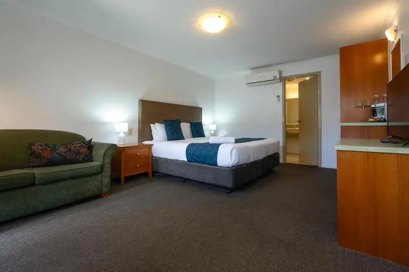 Une chambre lumineuse avec un lit double et un coin salon.