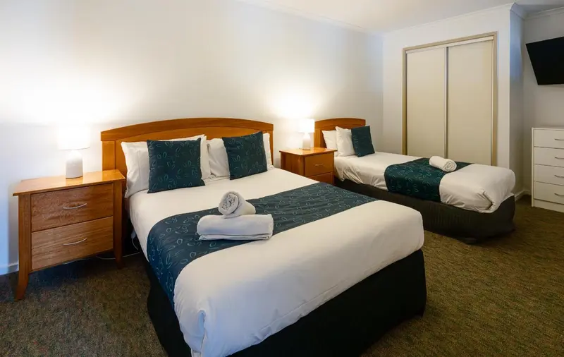 Une chambre lumineuse avec deux lits doubles décorés de coussins.