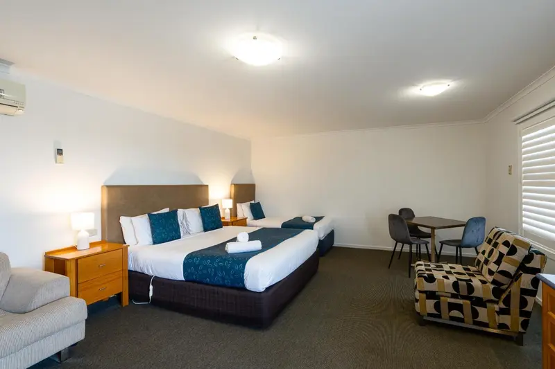 Une chambre lumineuse avec un grand lit et un coin repas.