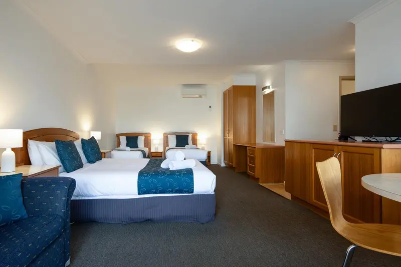 Une chambre d'hôtel lumineuse avec deux lits doubles et un coin salon.