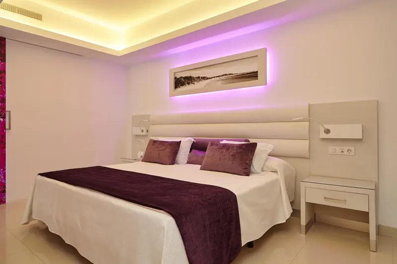 Une chambre lumineuse avec un grand lit et des oreillers violets.