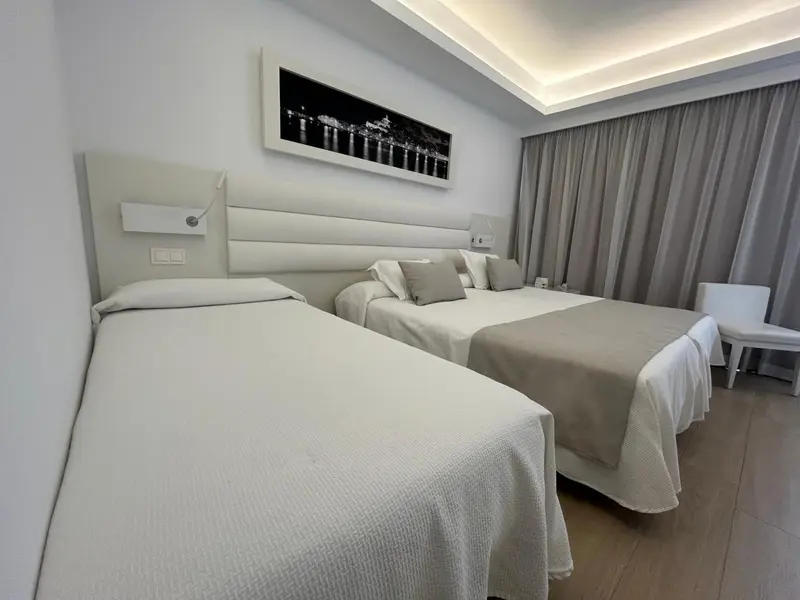 Une chambre lumineuse avec deux lits simples et une décoration sobre.
