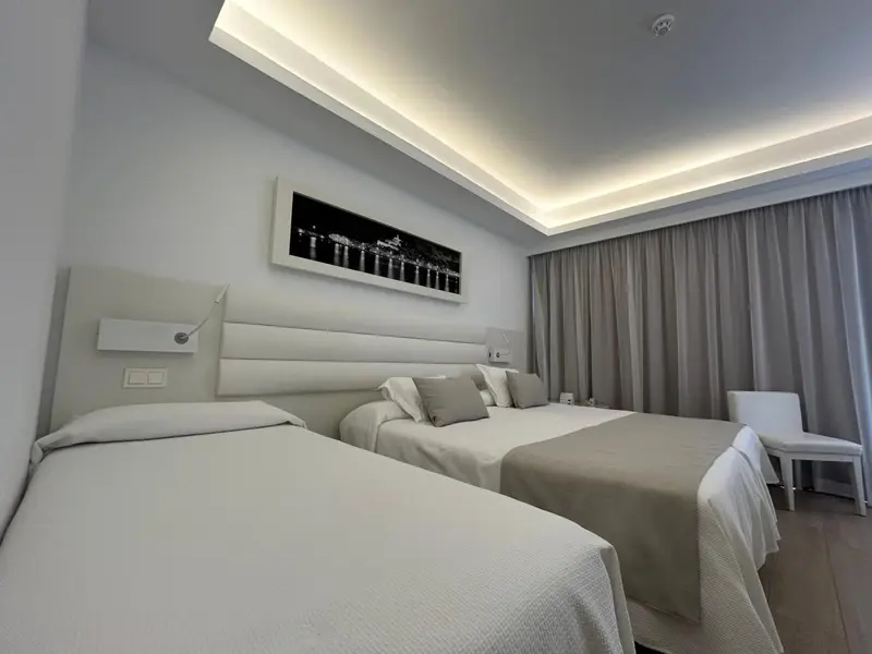 Une chambre lumineuse avec deux lits simples et une décoration sobre.