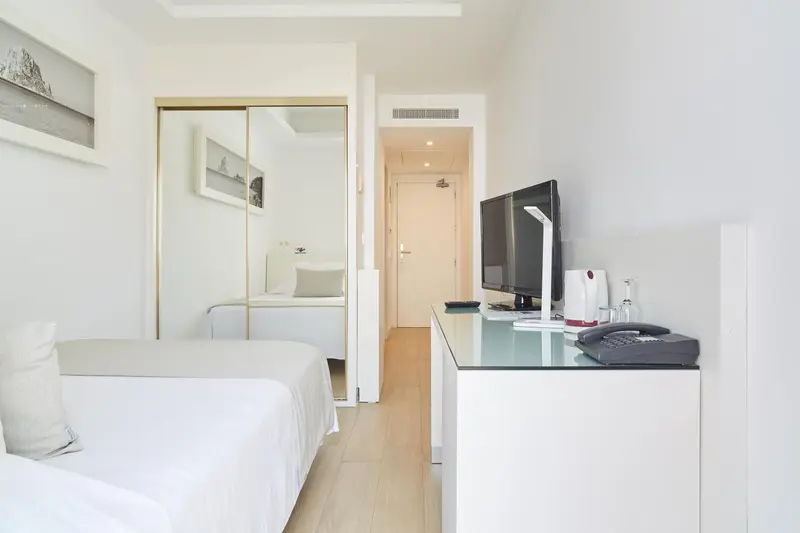 Une chambre lumineuse avec un lit et un meuble télévision.