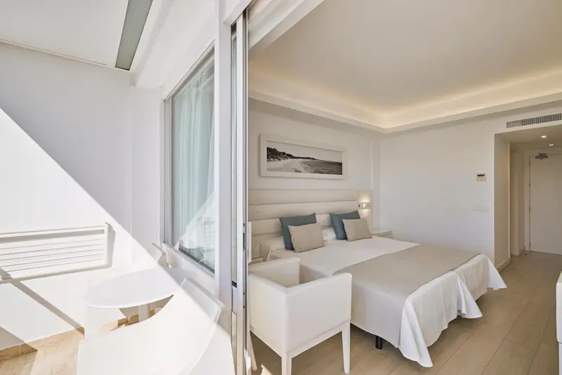 Chambre lumineuse avec un lit double et un coin salon.