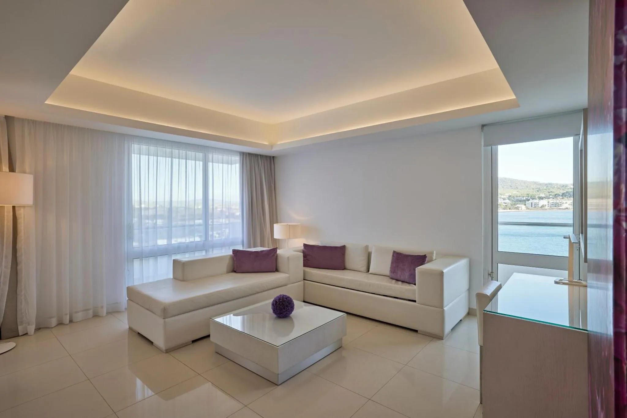 Espace de détente lumineux avec canapés blancs et vue sur la mer.