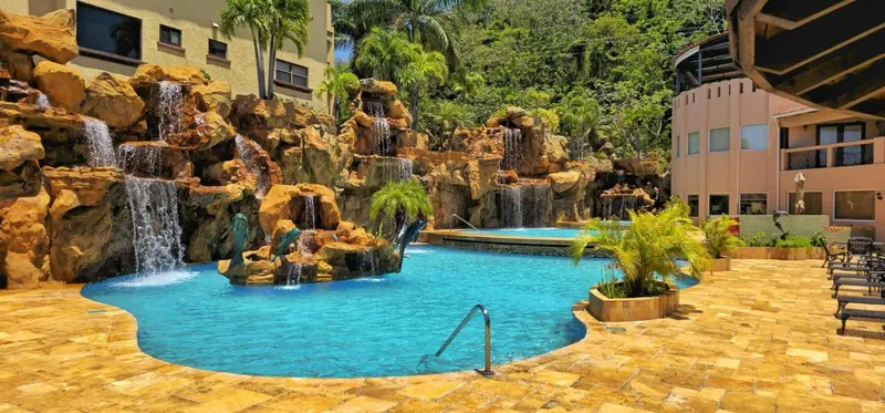 Une piscine turquoise est entourée de rochers artificiels et de cascades.