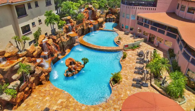 Vue aérienne d'un complexe hôtelier avec des piscines rocheuses et des palmiers.