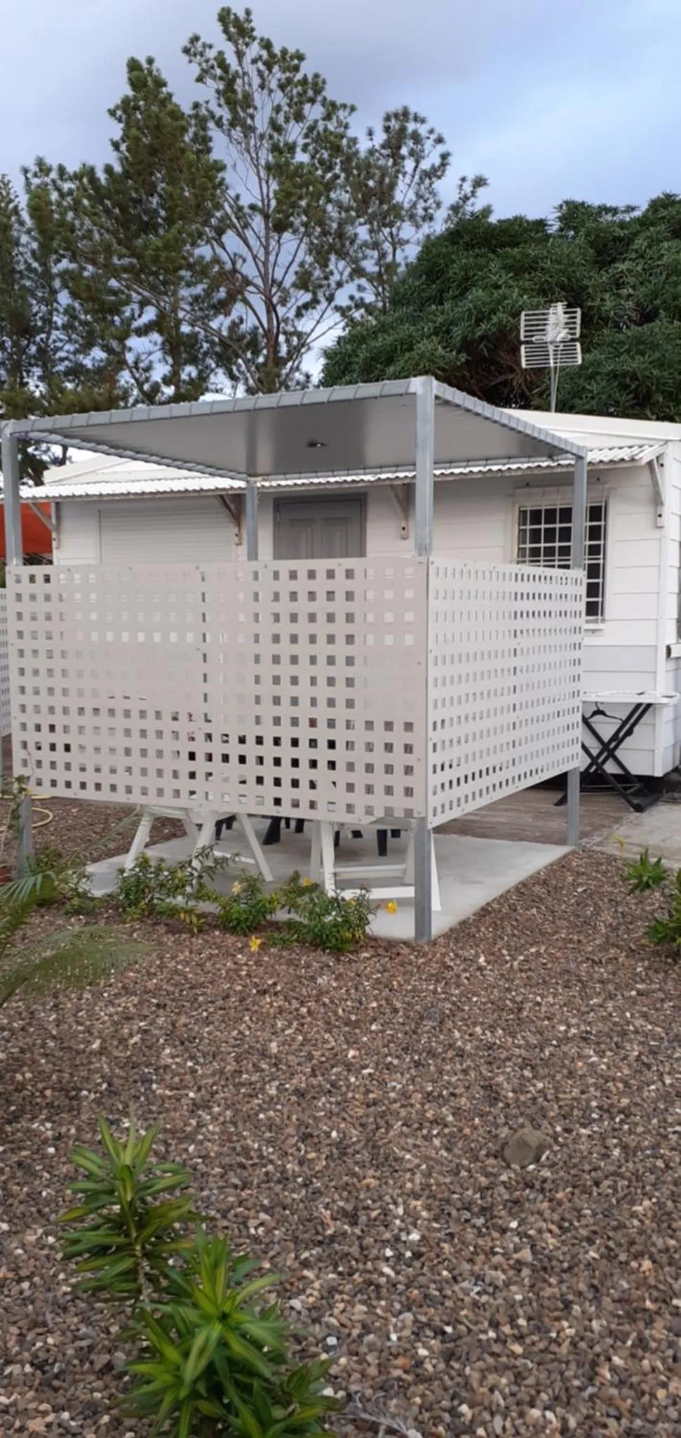 Abri de plage sur une terrasse en bois et gravier.