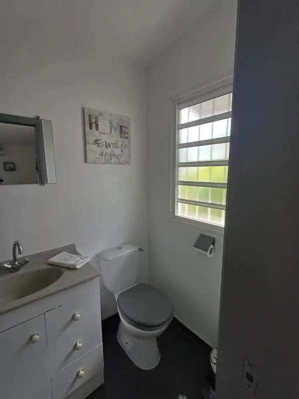 Une salle de bain claire avec lavabo, toilettes et fenêtre.