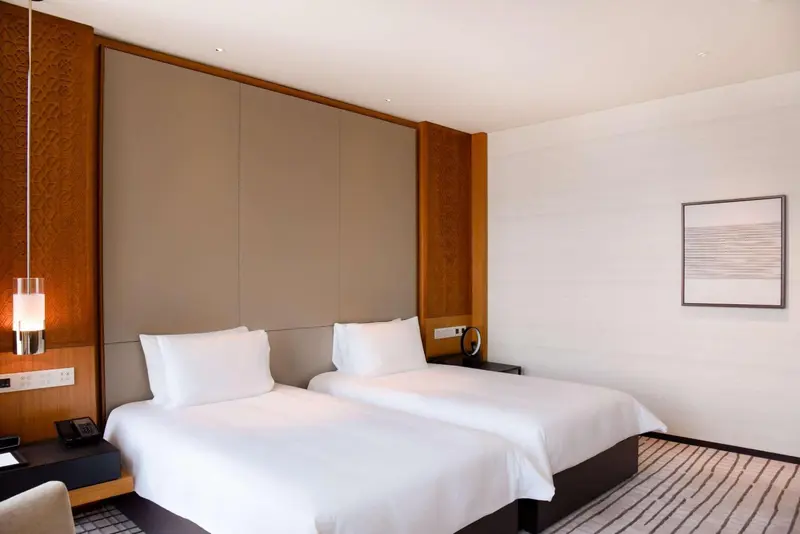 Une chambre lumineuse avec deux lits simples et une décoration sobre.