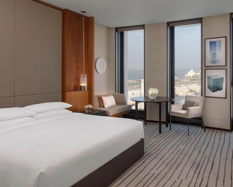 Une chambre lumineuse avec un grand lit et un coin salon près d'une fenêtre.