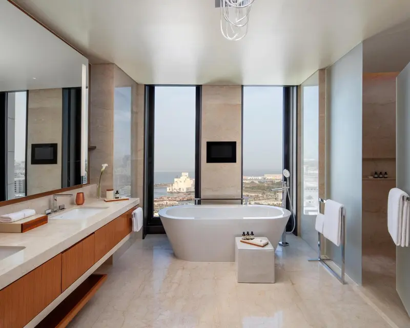 Une salle de bain lumineuse avec une baignoire et un grand miroir.