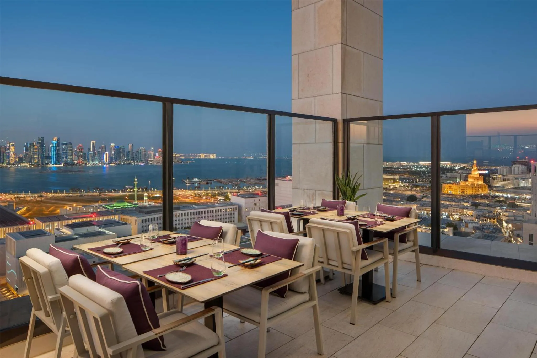 Une salle à manger avec vue sur la ville illuminée au crépuscule.