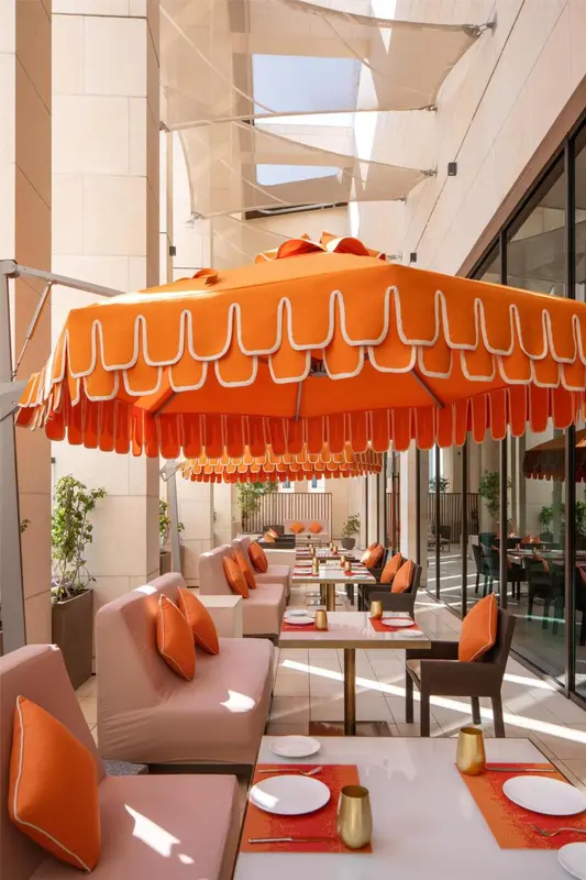 Tables et canapés disposés sous une marquise orange et blanche.